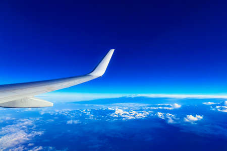 Wing of Plane at Blue Sky Background above Cloudsの写真素材