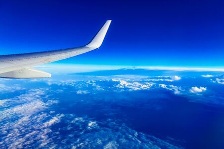 Wing of Plane at Blue Sky Background above Cloudsの写真素材
