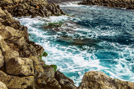 Beach Stones in Ocean or Sea Water with Waves and Foam Abstract Backgroundの写真素材