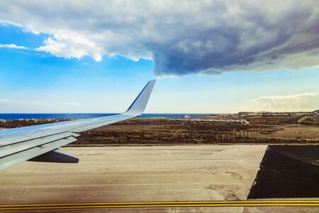 Wing of Plane at Tenerife Canary Island Coast Backgrond. View from Plane Runwayの写真素材