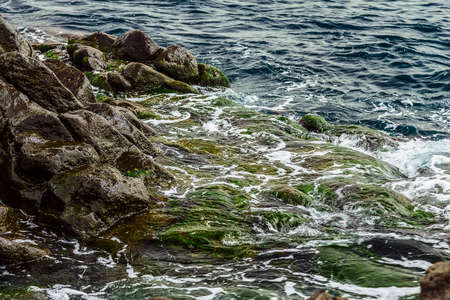 Beach Stones in Ocean or Sea Water with Waves and Foam Abstract Backgroundの写真素材