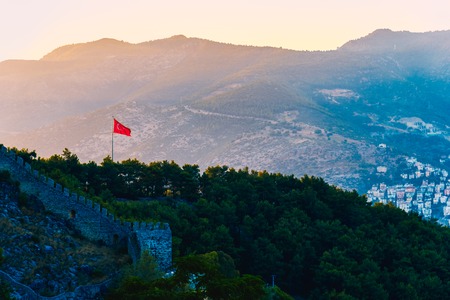View of Turkish flag on castle of Alanya on top of mountains at sunny day, Turkeyの写真素材