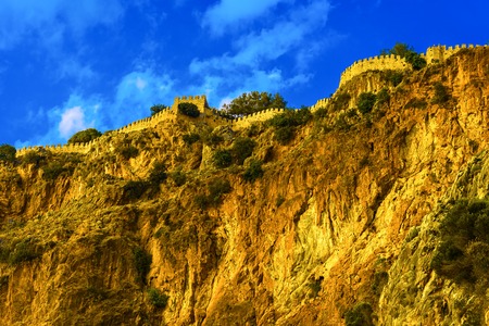 Castle wall on hill on background of blue sky with clouds in Alanya, Turkeyの写真素材