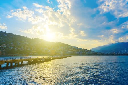 Long pier at the entrance to the seaport and mountain views in Alanya at sundown, Turkeyの写真素材