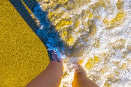 Female legs on sand beach and sea waves at sunny day in Alanya, Turkeyの写真素材