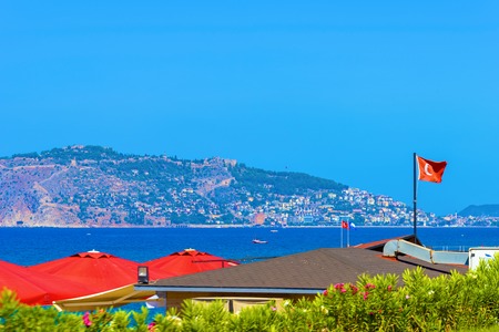 Waving Turkish flag on roof building against background of Alanya  city and sea, Turkeyの写真素材