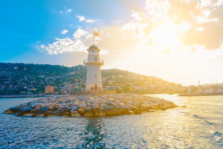 Lighthouse in the port of Alanya with view on beach and mountain in Turkey at sunsetの写真素材