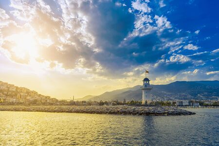 Lighthouse in the port of Alanya with view on beach and mountain in Turkey at sunsetの写真素材