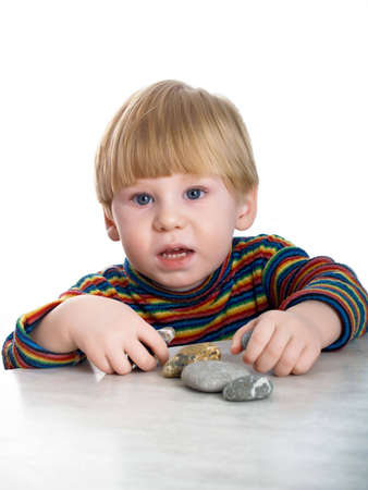 The little boy is played with stones on a tableの写真素材