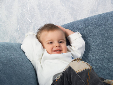 The little boy lays on a sofa of the houseの写真素材