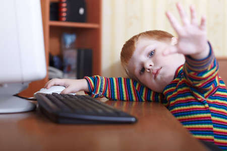 The little boy plays on a computer in a roomの写真素材