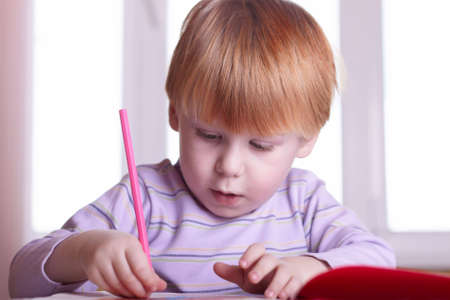 boy with the book behind a table on the black backgroundの写真素材