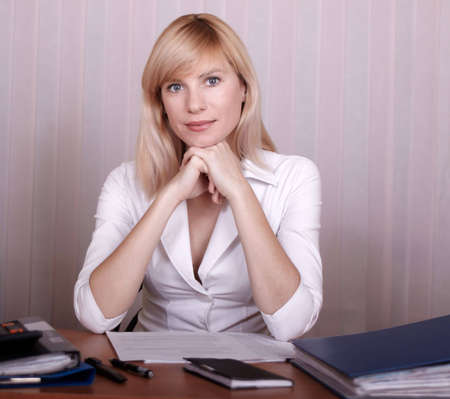 Businesswoman sits at a table in white clothesの写真素材