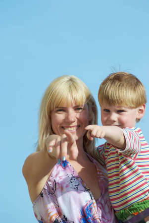 Mum with the small son on hands on a background of the dark blue skyの写真素材