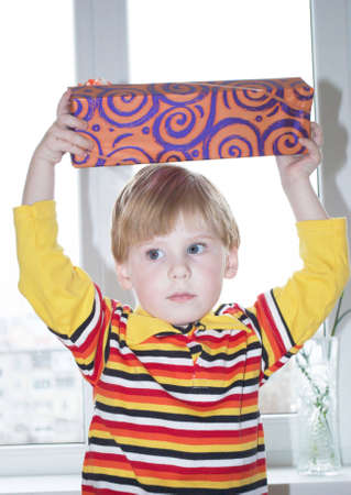 Portrait of the little boy with a gift box on a backgroundの写真素材