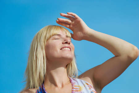 The young woman poses with the lifted hands on a background of the dark blue skyの写真素材