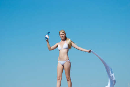 The woman in a bathing suit holds a bottle with water in the summerの写真素材