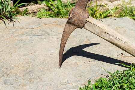 Pickax has a gray stone on top. Extraction of stone and iron ore using a hoe or a hammer with a wooden handle. Stone and around the green grass.の写真素材
