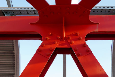 Red iron beams bolted. Asymmetrical connection of several iron beams in one place.