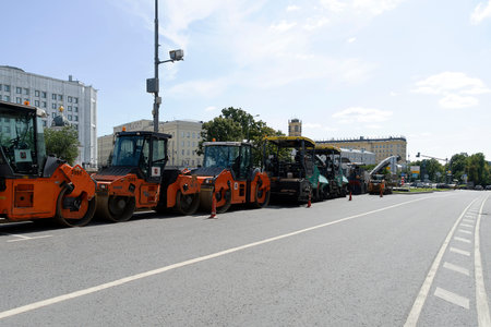 Russia, Moscow, 2019-08-10. Road equipment in a row stands on the road. Paver and road roller....