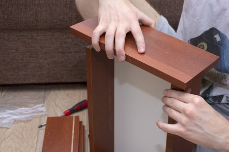 A male tool collects furniture color spanish walnut. Assembly of a desk drawer cover.の写真素材