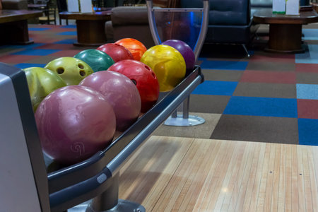 Bowling balls lie in a holder in a line. Colored balls and bowling lane.