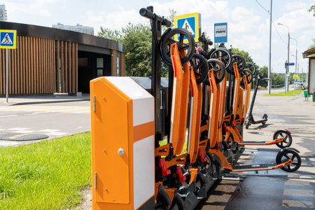 Scooter rental station near the road. Orange scooters in defense. Paid rental of scooters in the...