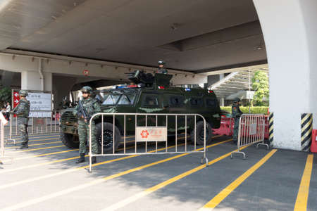 GUANGZHOU, CHINA, 2019-10-17: Chinese military with weapons near an armored car, guarding the passage and passage. Security of the facility, a checkpoint under a concrete bridge. Checkpoint with military guards wearing helmets, bulletproof vests and weapoのeditorial素材