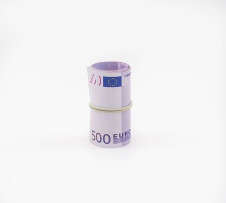 Banknotes five hundred and 500 euros in a roll with an elastic band. European currency to save. Close-up, white background. The concept of the safety of deposits and money.の写真素材