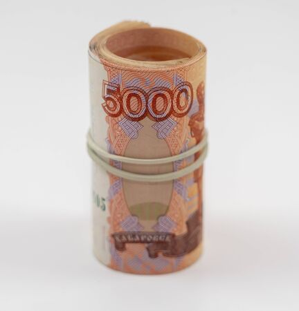Banknotes five thousand rubles 5000 in a roll with an elastic band. Russian currency to save. Close-up, white background. The concept of the safety of deposits and money.の写真素材