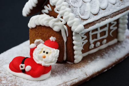 Santa Claus in front of gingerbread house.の写真素材