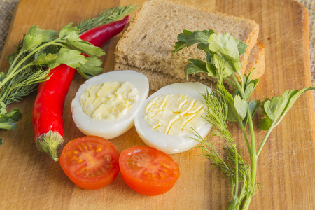 boiled egg, tomato, pepper on cutting boardの写真素材