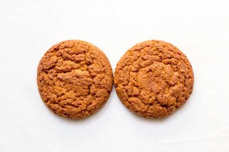 two round oatmeal cookies on a white backgroundの写真素材