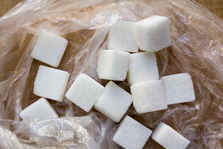 White sugar pieces in a plastic bag on a wooden background.の写真素材
