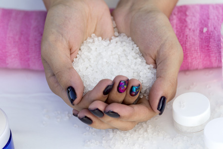 Hands girl with beautiful manicure on a pink towel keep cosmetic salt.の写真素材