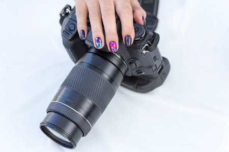 single-lens reflex camera in the hands of a girl with a beautiful manicure on white background
