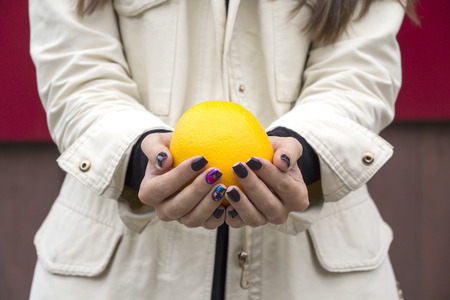 Hands girl with fashionable manicure keep oranges on the streetの写真素材
