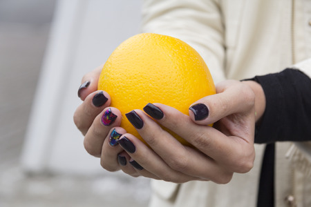At the hands of the girl with the fashionable manicure fresh, bright orange liesの写真素材