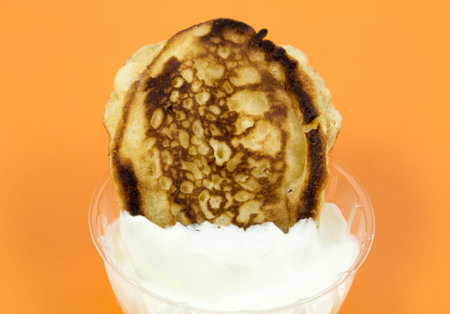 Closeup of a gingerbread pancake with a cream on a yellow background