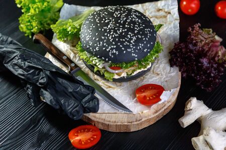 Black burger on a napkin on a black backgroundの写真素材