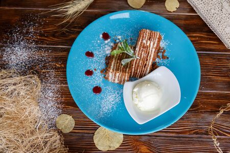 Ice cream ball and pieces of cake on a blue plate on a wooden backgroundの写真素材