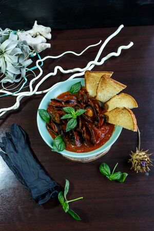 Mussels in tomato sauce with garlic in a blue plate on a brown wooden backgroundの写真素材