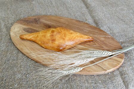Appetizing Uzbek samsa from puff pastry on a kitchen board with a spikelet of wheatの写真素材