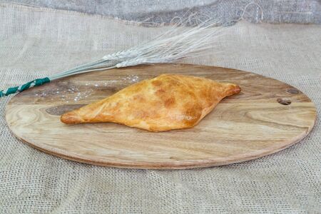 Appetizing Uzbek samsa from puff pastry on a kitchen board with a spikelet of wheatの写真素材