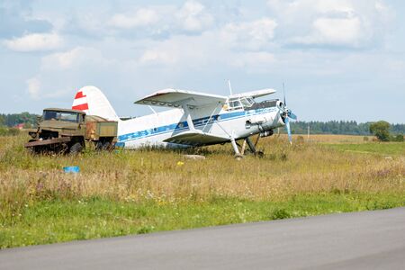 Double plane and an old truck stand in a clearing against the background of trees on a sunny summer dayの写真素材