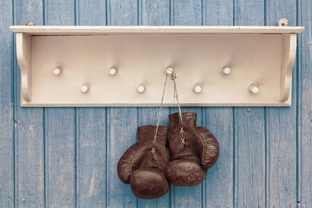 Old boxing gloves hanging on the white wooden hangerの写真素材