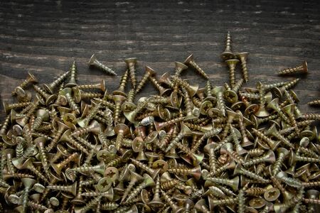 Many screws lying on a wooden boardの写真素材