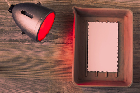 Photographic paper shows up in a cuvette and red laboratory lanternの写真素材