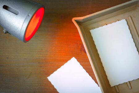 Photographic paper shows up in a cuvette and red laboratory lanternの写真素材