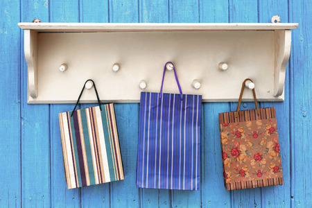 Three gift paper bags hanging on white wooden hangerの写真素材